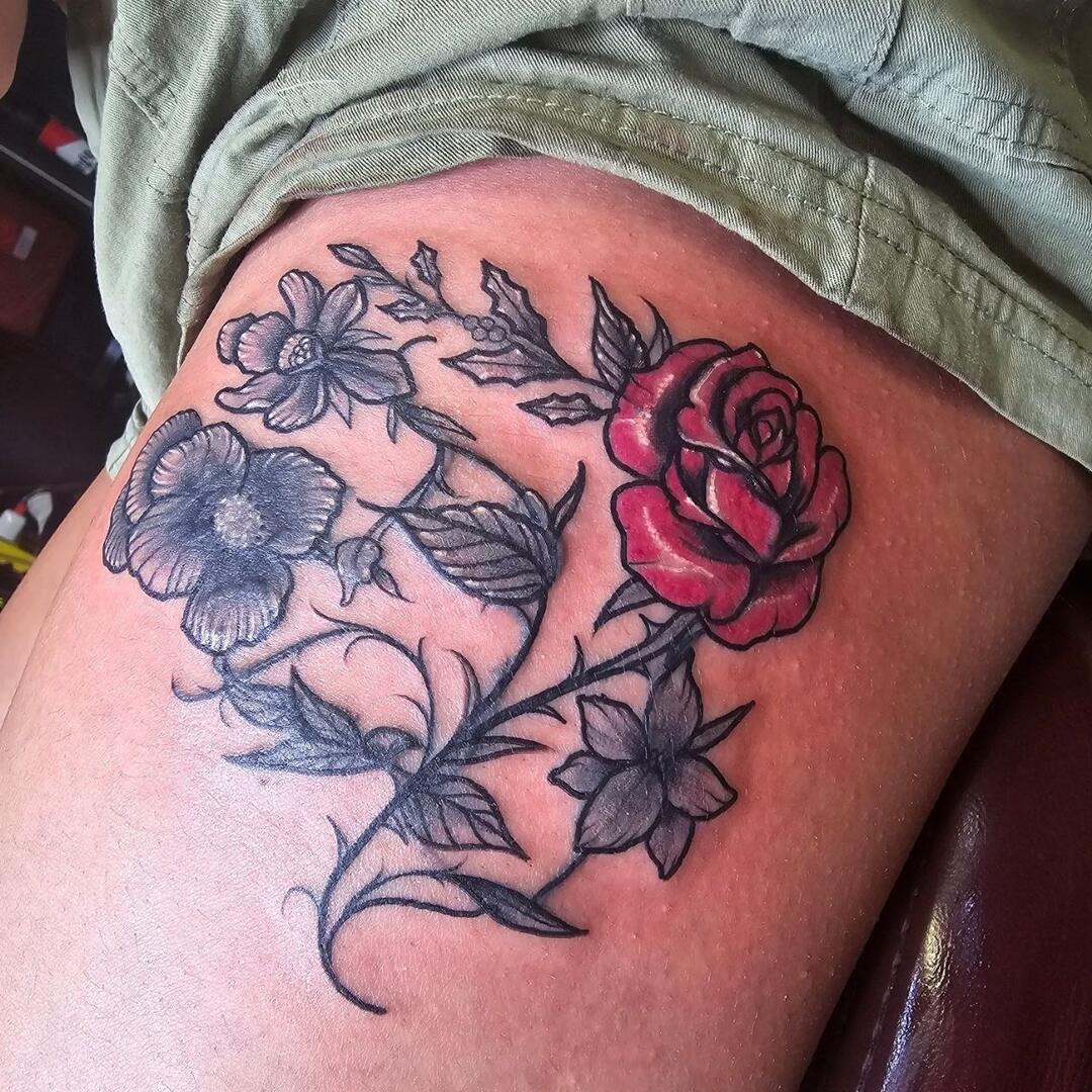 Colour rose with black-and-grey florals tattooed on a thigh