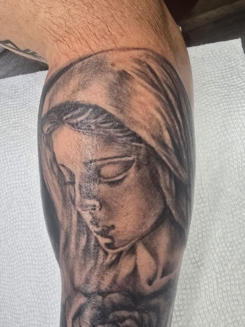 Black-and-grey religious portrait tattoo on a forearm