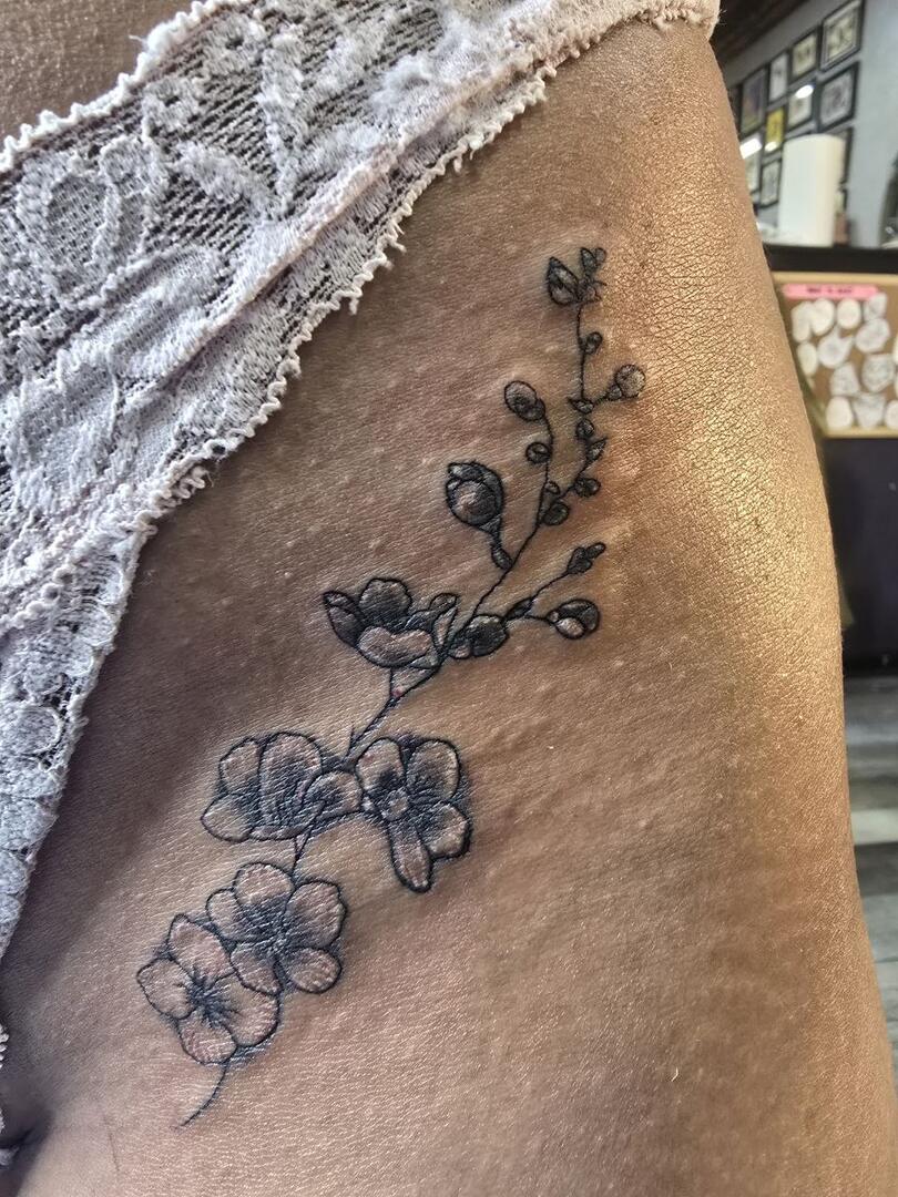Fine-line orchid tattoo on a hip