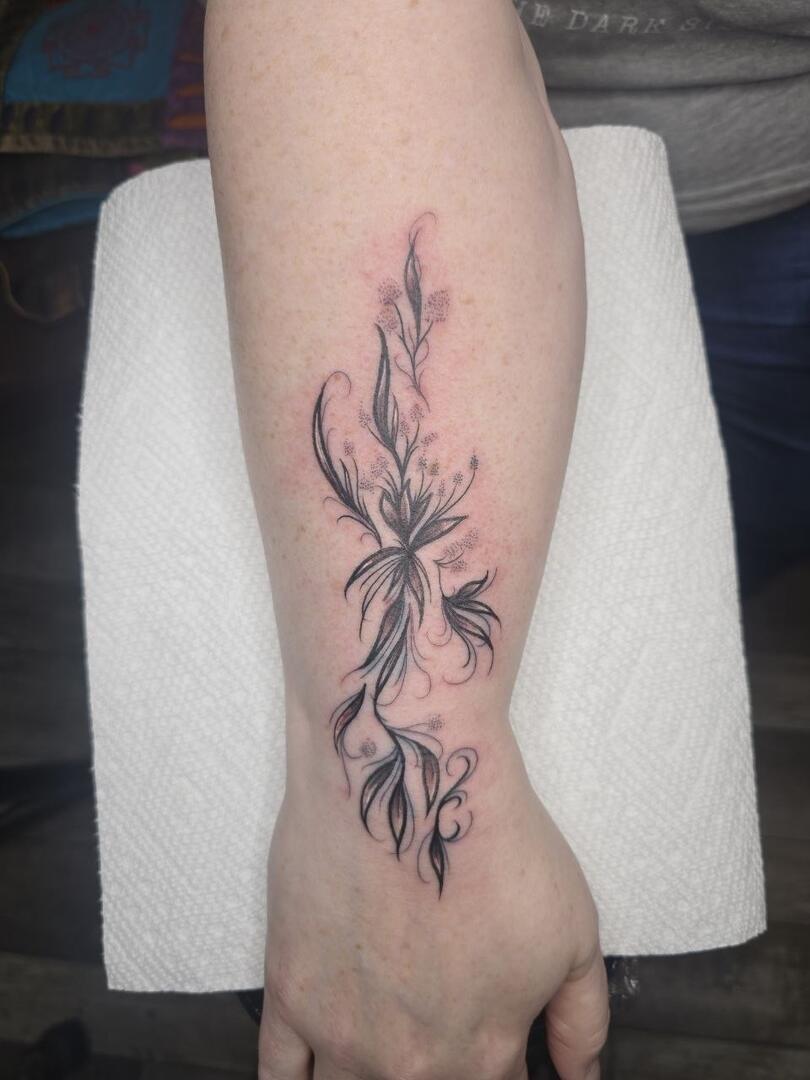 Fine-line botanical tattoo on a forearm