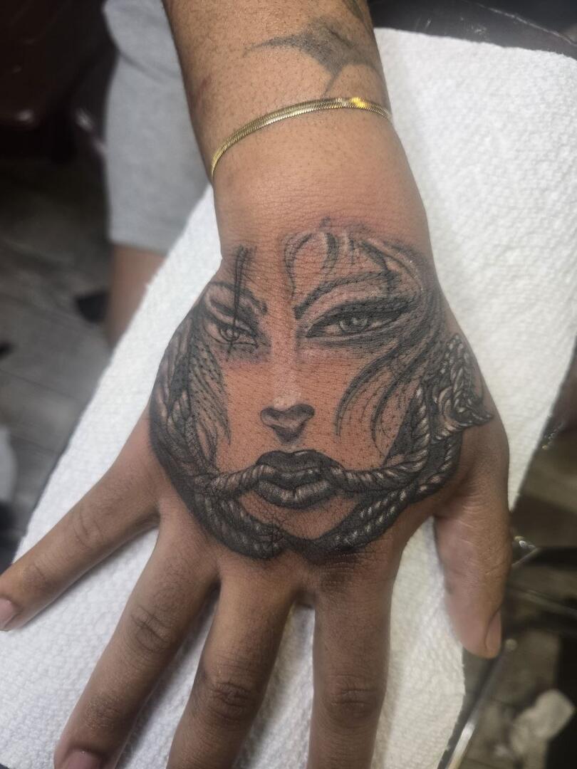 Black-and-grey woman portrait tattooed on a hand