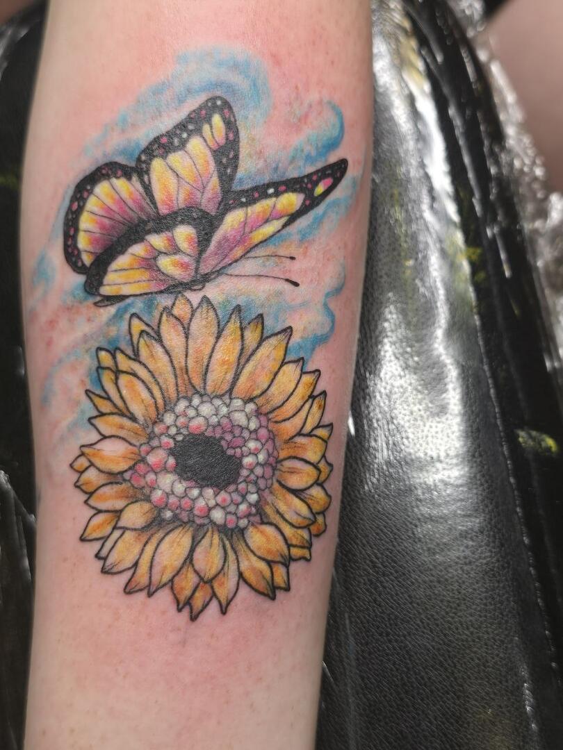 Colour sunflower and butterfly tattoo on a forearm